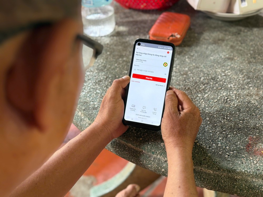Ông Huỳnh Phước Hùng được con hướng dẫn vào VNeID để liên kết tài khoản an sinh xã hội. Ảnh: HẢI NHI Tết Độc lập (3).jpg