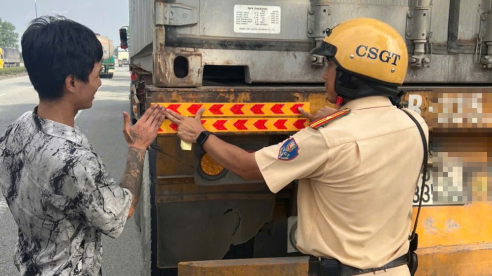CSGT hỗ trợ dán đề can phản quang ở phần đuôi xe tải, xe container… giúp người đi đường dễ nhận diện phương tiện vào ban đêm. tp-hcm-csgt-xu-ly-nghiem-xe-tai-xe-khach-vi-pham-giao-thong (3).jpg