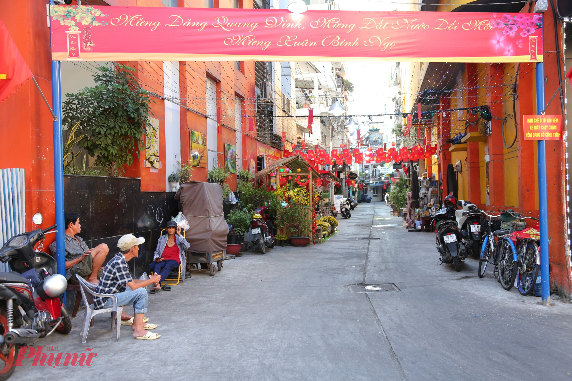 Tại phường Bến Thành, không khí Tết Bính Ngọ 2026 đã hiện diện rõ nét trong nhiều con hẻm rộng như hẻm 100 Trần Hưng Đạo, hẻm 153 Nguyễn Thị Minh Khai, hẻm 353 Phạm Ngũ Lão… Những con hẻm quen thuộc ngày thường nay được trang trí bằng hoa tươi, đèn lồng, tiểu cảnh Tết mang đậm hương vị truyền thống, tạo nên những “đường hoa mini” đầy màu sắc giữa lòng đô thị sôi động.