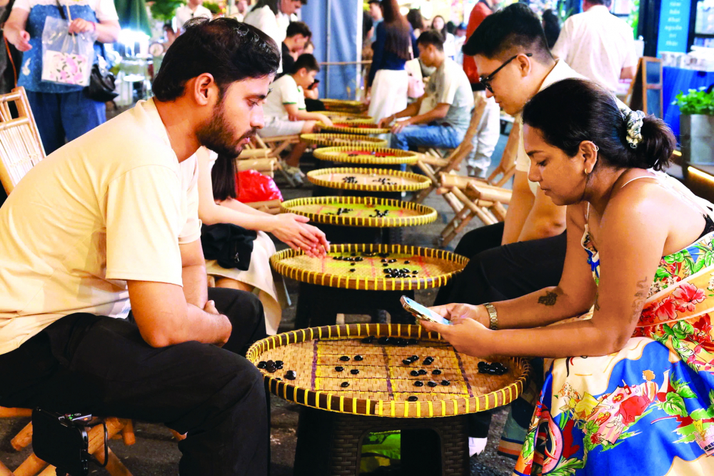 TPHCM vươn tầm thế giới từ cội nguồn, giá trị văn hóa dân tộc Du khách nước ngoài trải nghiệm trò chơi ô ăn quan tại ngày hội Sách và Văn hóa đêm tại Đường sách TPHCM - ẢNH: HỒNG NGA