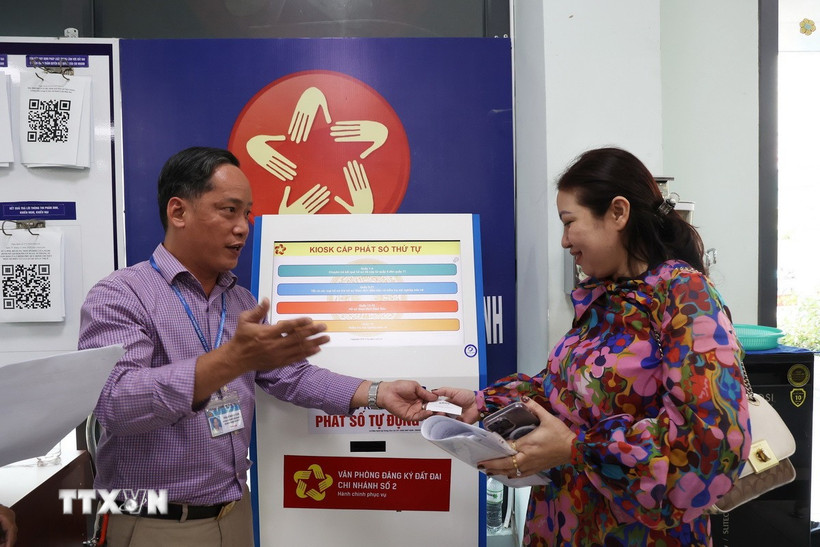 Hỗ trợ người dân đăng ký dịch vụ và lấy số thứ tự tại Văn phòng Đăng ký đất đai Thành phố Hồ Chí Minh. (Ảnh: Hồng Đạt/TTXVN)