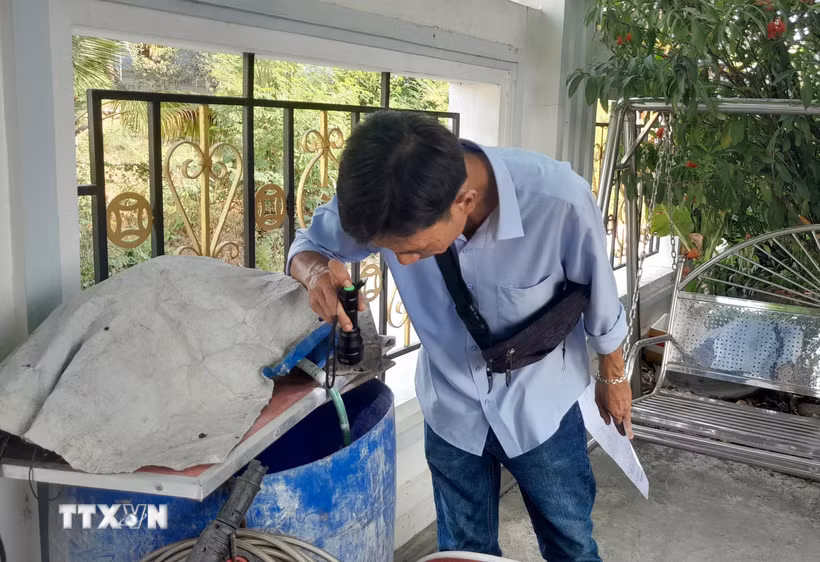 Kiểm tra các thùng phuy chứa nước trong gia đình, môi trường muỗi sinh sản loăng quăng. (Ảnh: TTXVN)