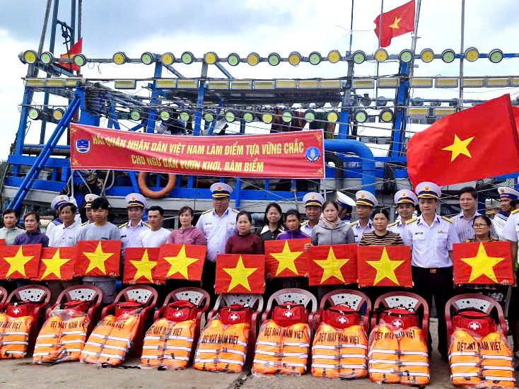 Tặng cờ Tổ quốc, áo phao, phao cứu sinh, túi y tế cho ngư dân tại cảng cá Bình Châu. Ảnh: THÀNH HUY