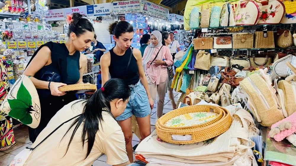Du khách nước ngoài chọn mua đồ lưu niệm tại chợ Bến Thành (TPHCM). Ảnh: THI HỒNG