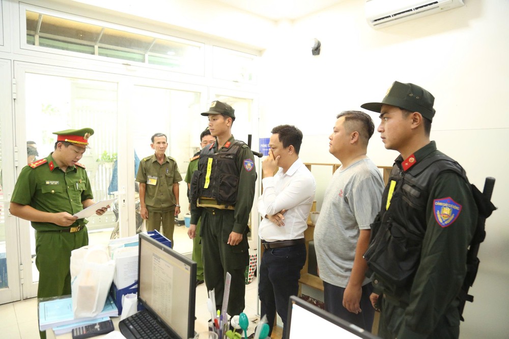 Công an đọc lệnh khám xét. Ảnh: CATP khoi-to-5-vu-an-bat-21-nguoi-lam-gia-ket-qua-quan-trac-moi-truong (1).jpg
